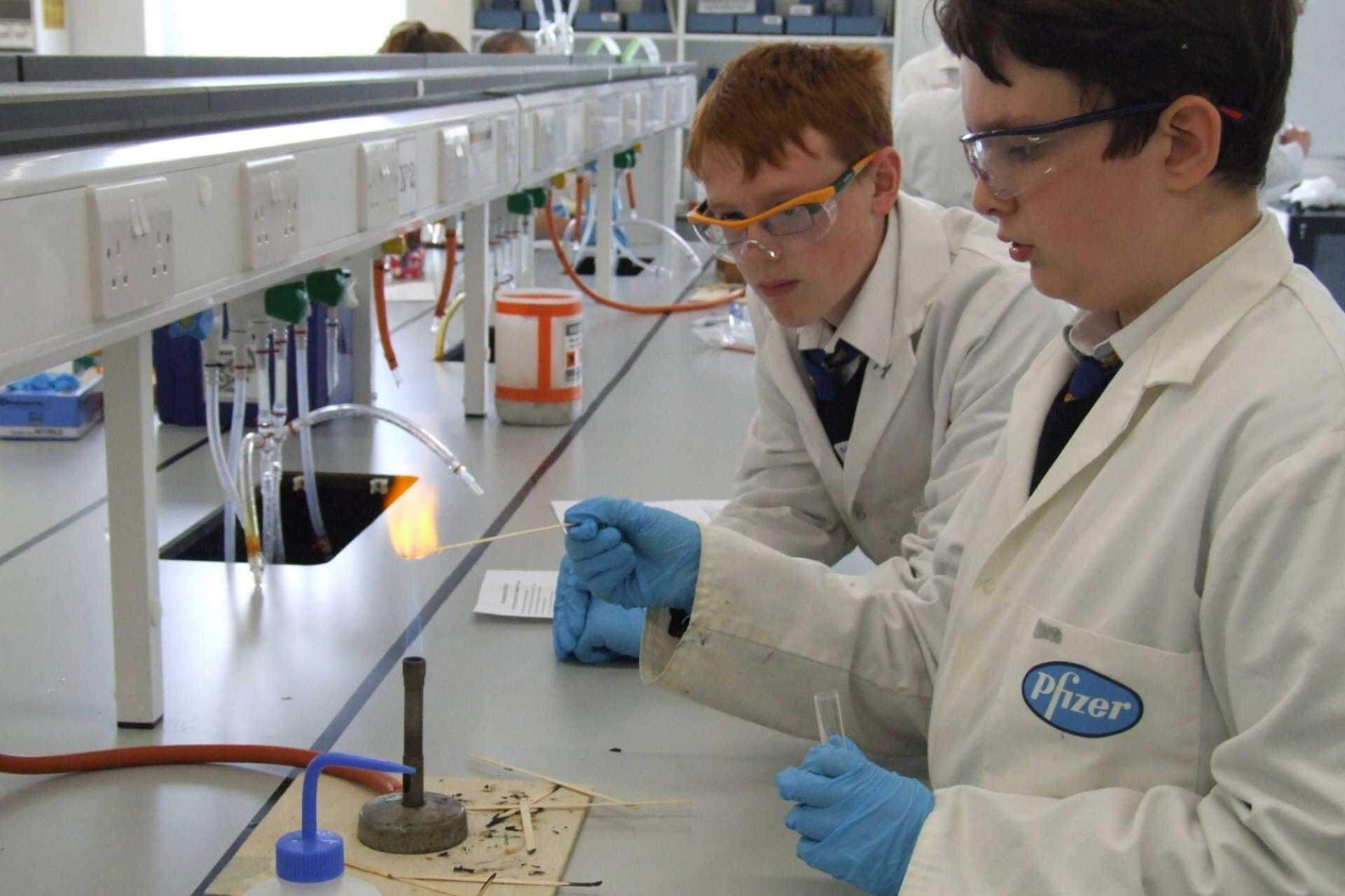 Two school students working with Bunsen burner in laboratory