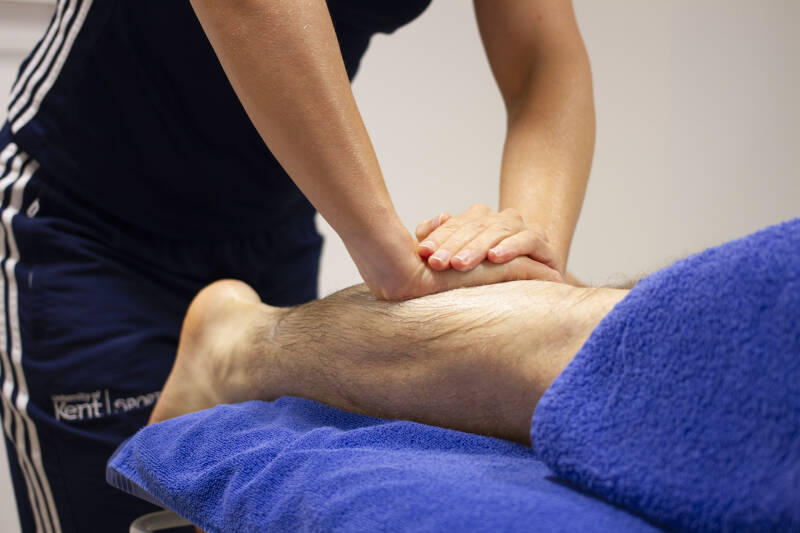 Qualified massage therapist massaging a clients leg during an appointment