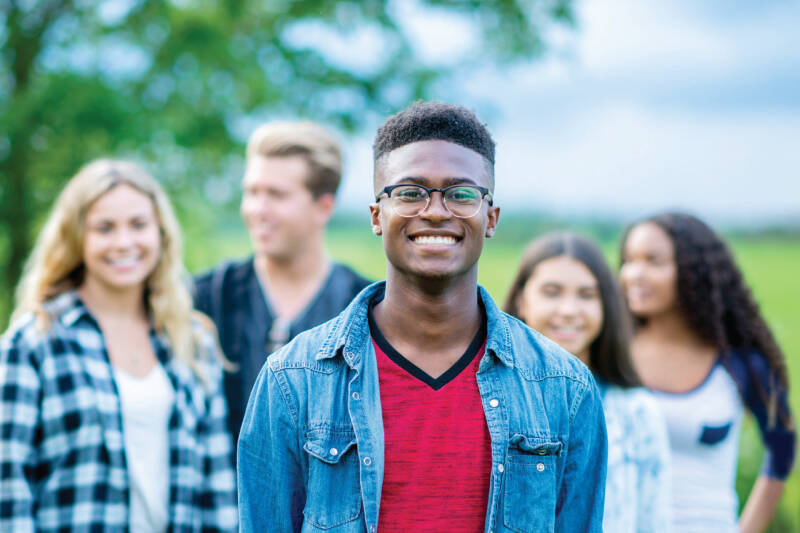A smiling student standing in front of a group of more students