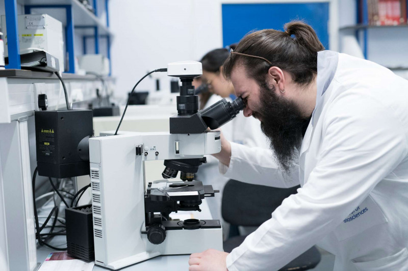 Male and female student using microscopes