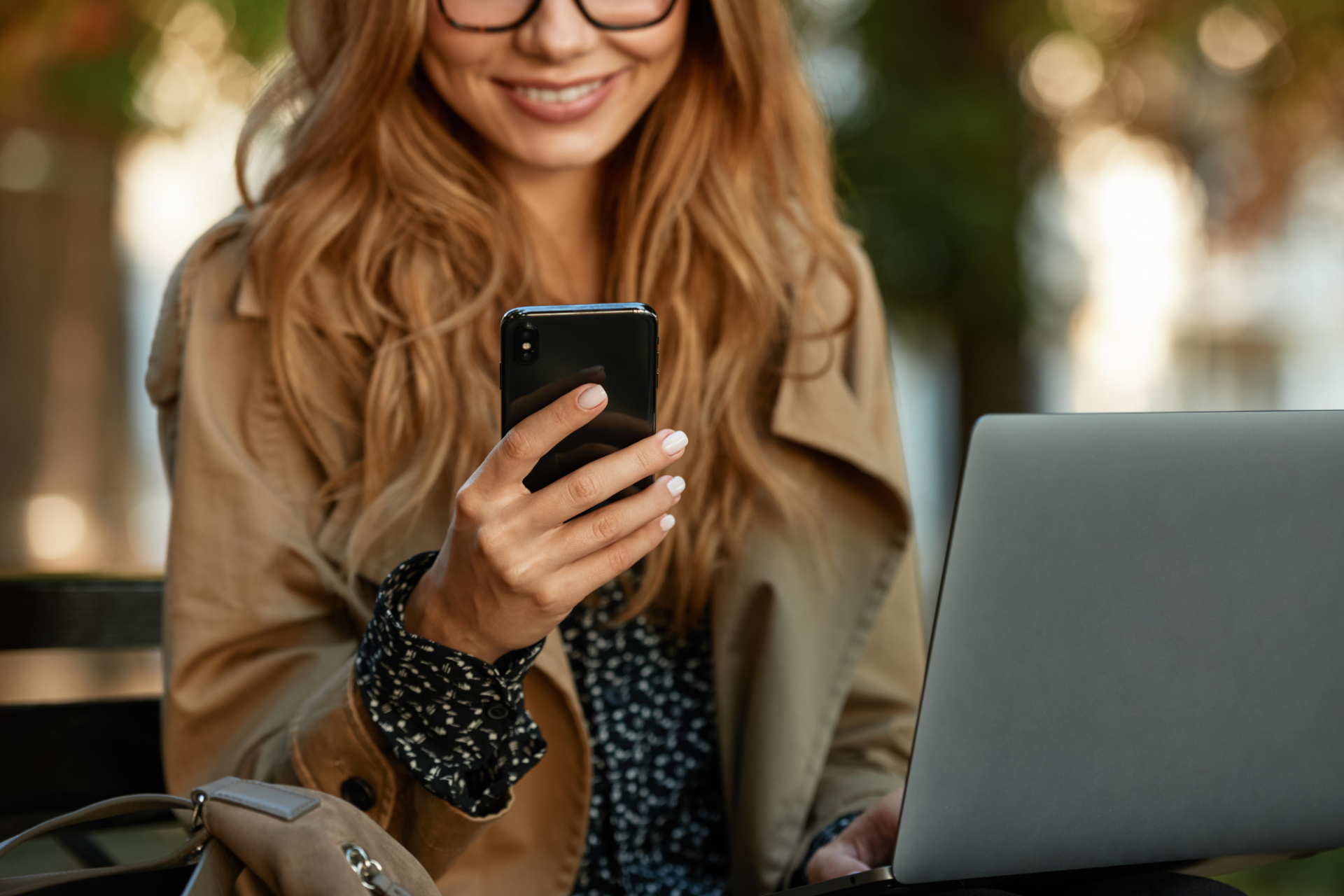 Woman smiling using laptop and phone