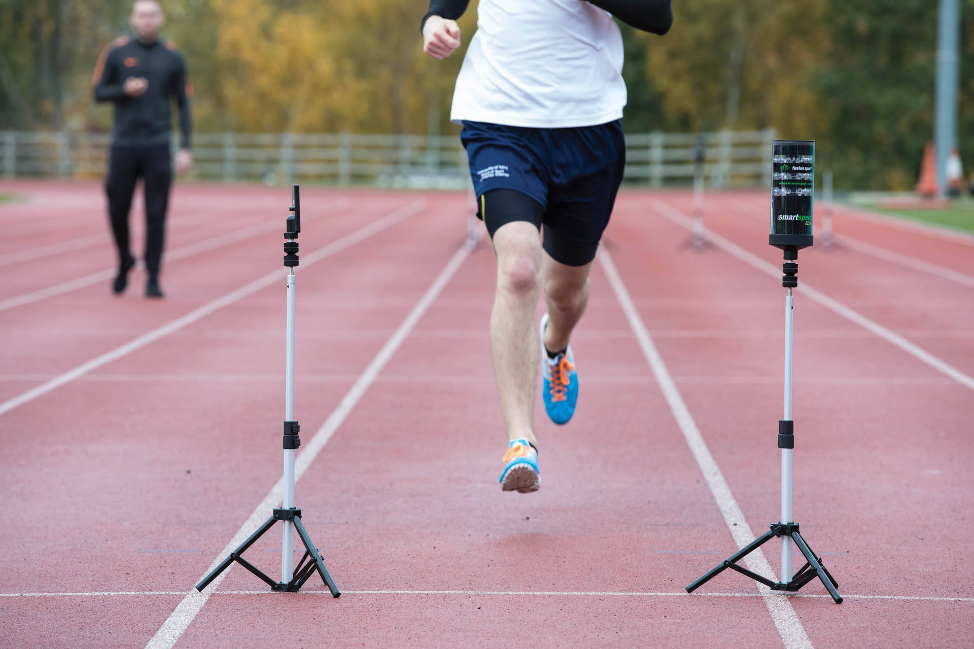 Person running on an outdoor track, between monitoring equipment.