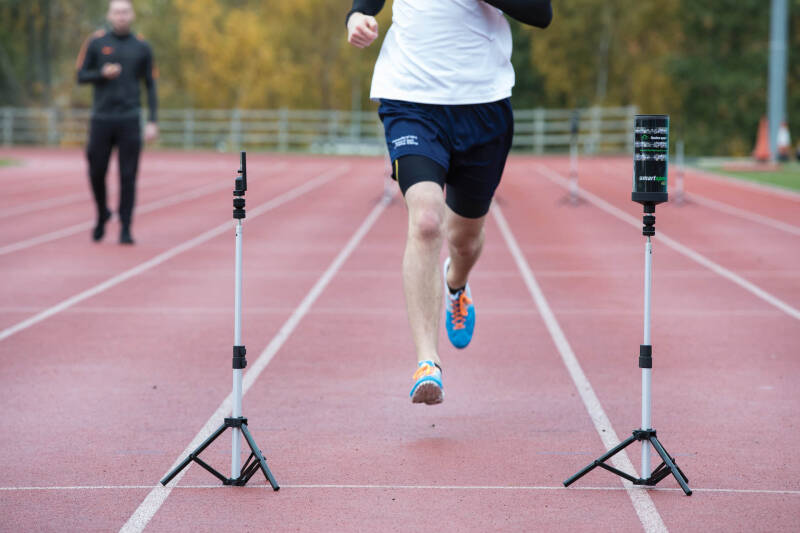 Person running on an outdoor track, between monitoring equipment.