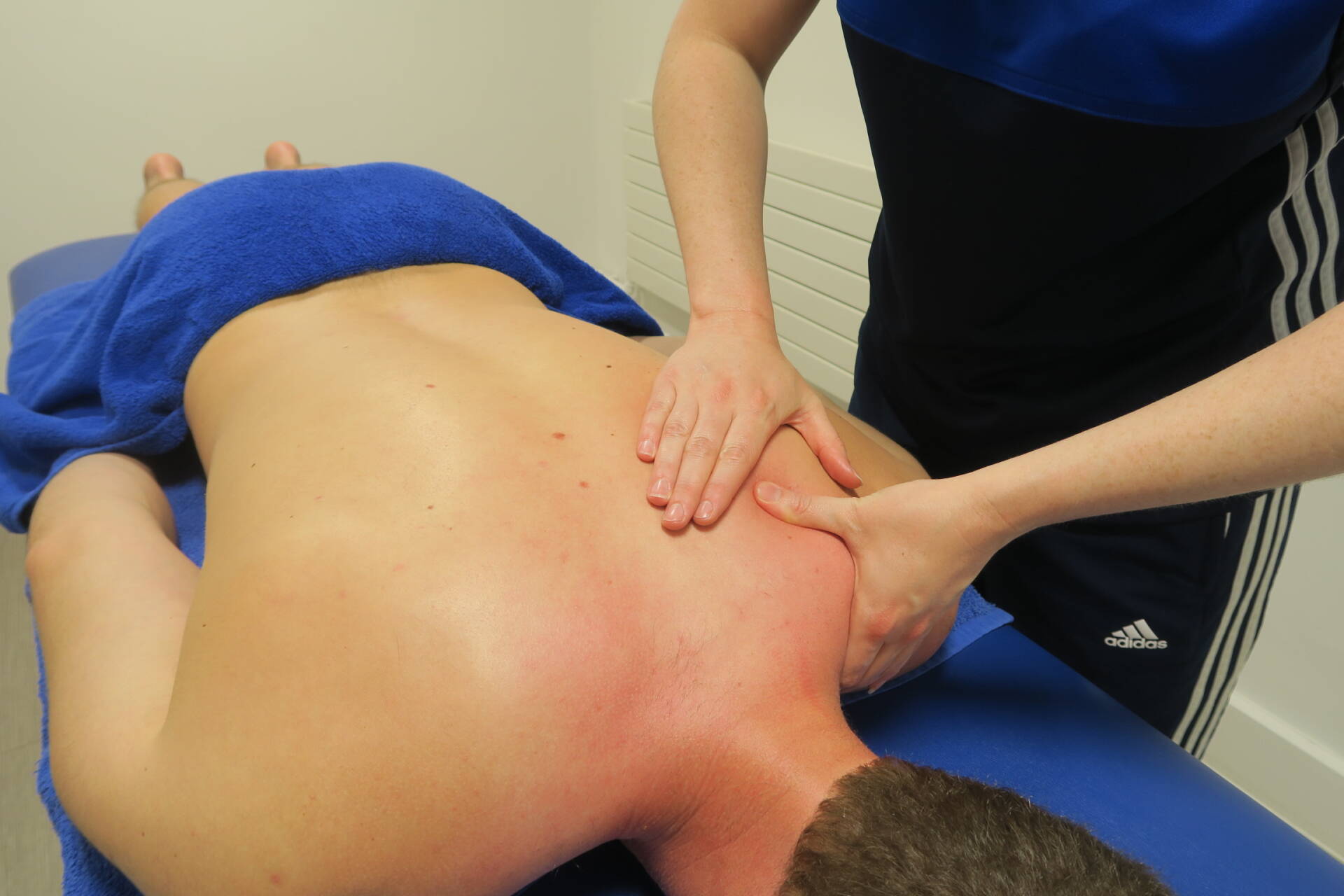Qualified massage therapist assessing a clients shoulder during a massage appointment.