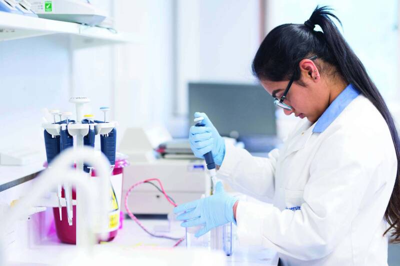Student in a lab working with multiple large blue pipets