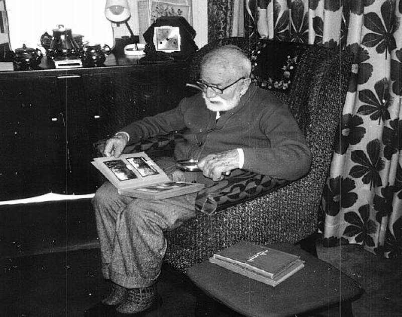 Photograph of William Muggeridge looking at an album of windmill images.