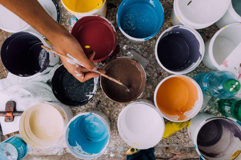 Photo of multiple pots of paint with someone using a paintbrush