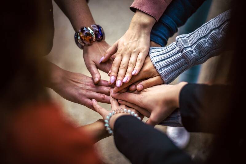 A circle of people touching hands in the centre