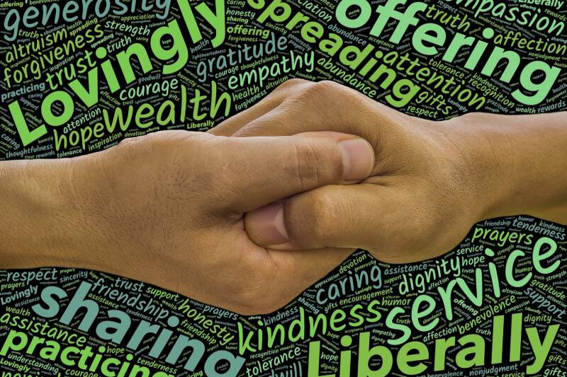 Two people linking hands while words describing compassionate emotions surround them