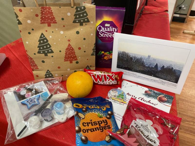 Christmas goody bad showing contents that includes chocolates and a craft set.