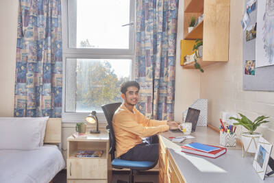 Eliot College standard bedroom with male student at his desk
