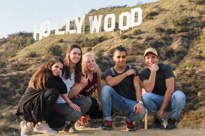 Group of students crouching in front of Hollywood sign.