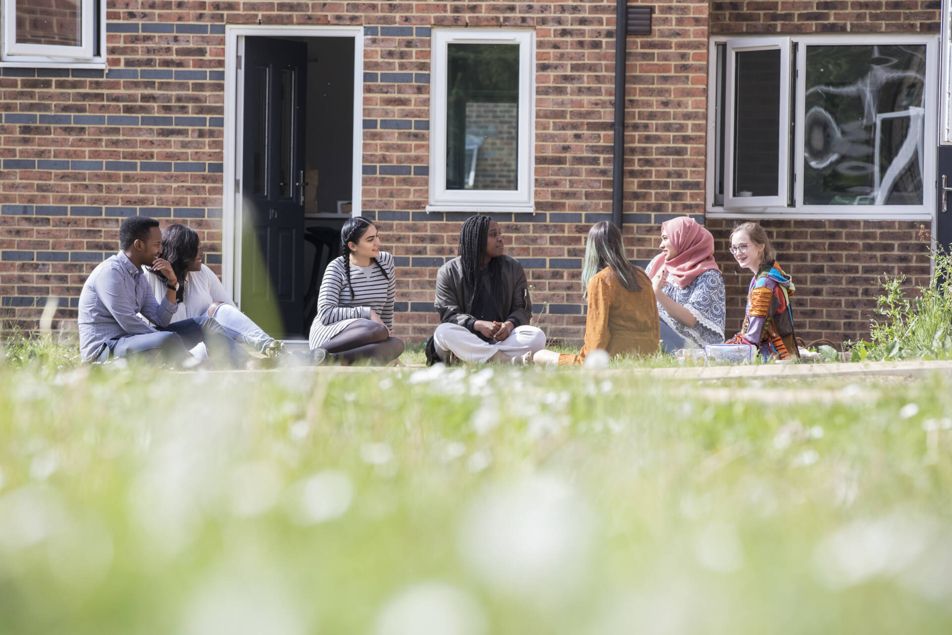 Group of students chatting on grass outside of a Park Wood House