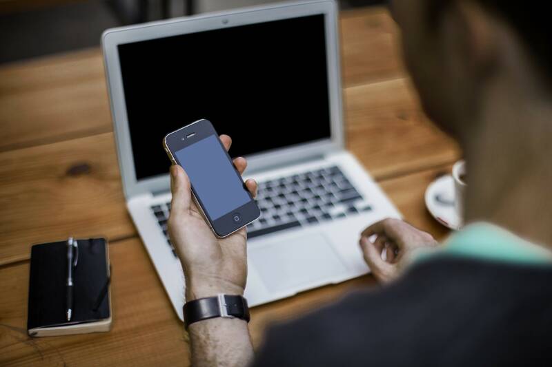 A man using his phone and laptop