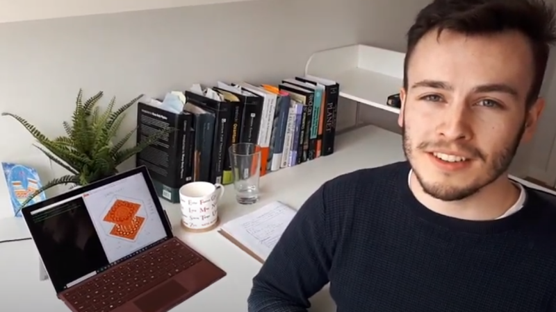Henry Sheehy in his room with books and a laptop in the background.