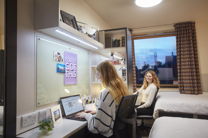 Two female students working at desk in twin room