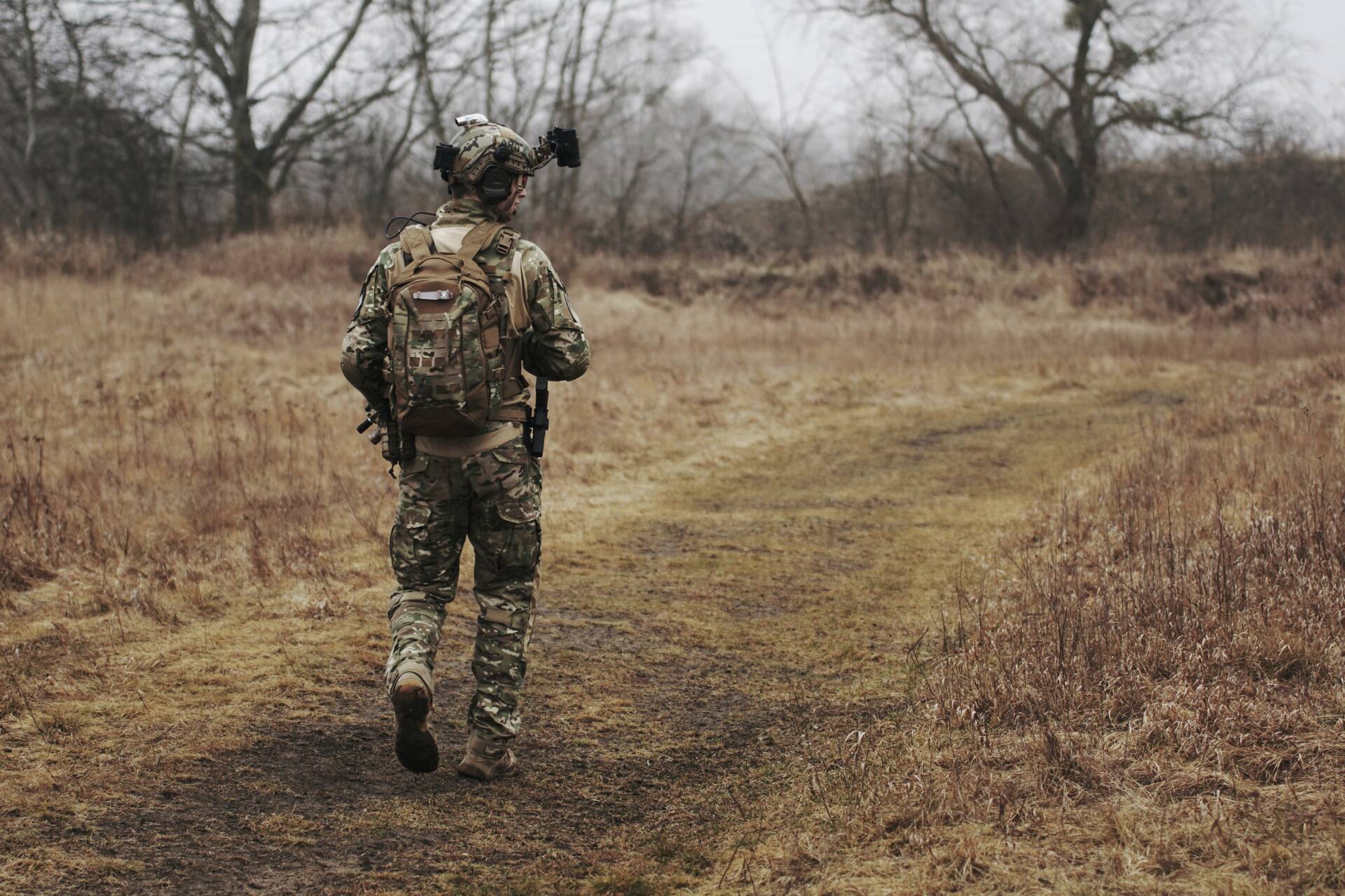 a soldier in camouflage clothing walking away from the camera