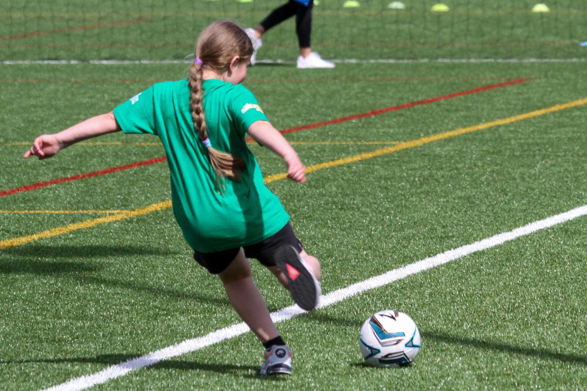 Child in a green t-shirt about to kick a football