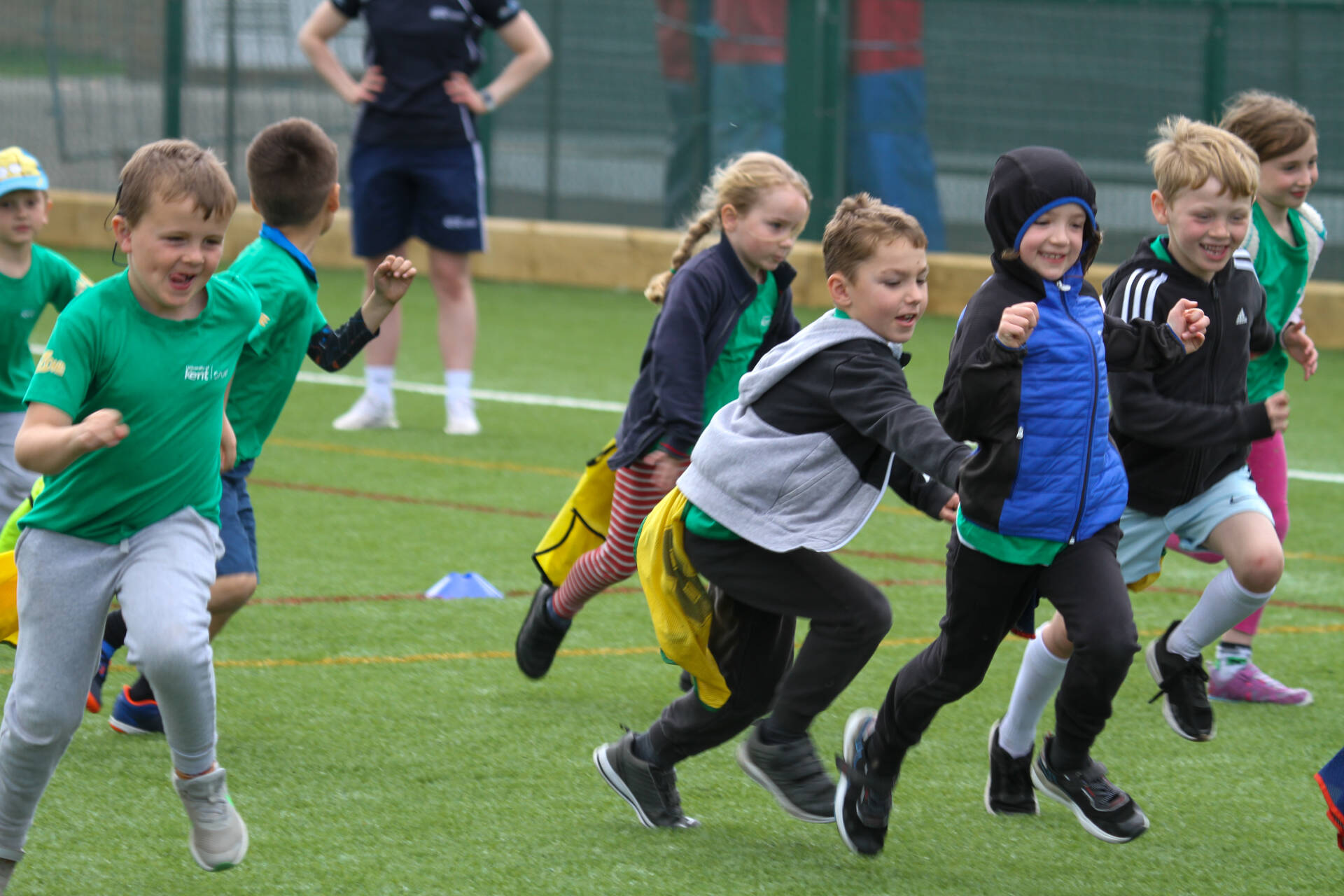 Children chasing each other on artificial pitch playing tag rugby
