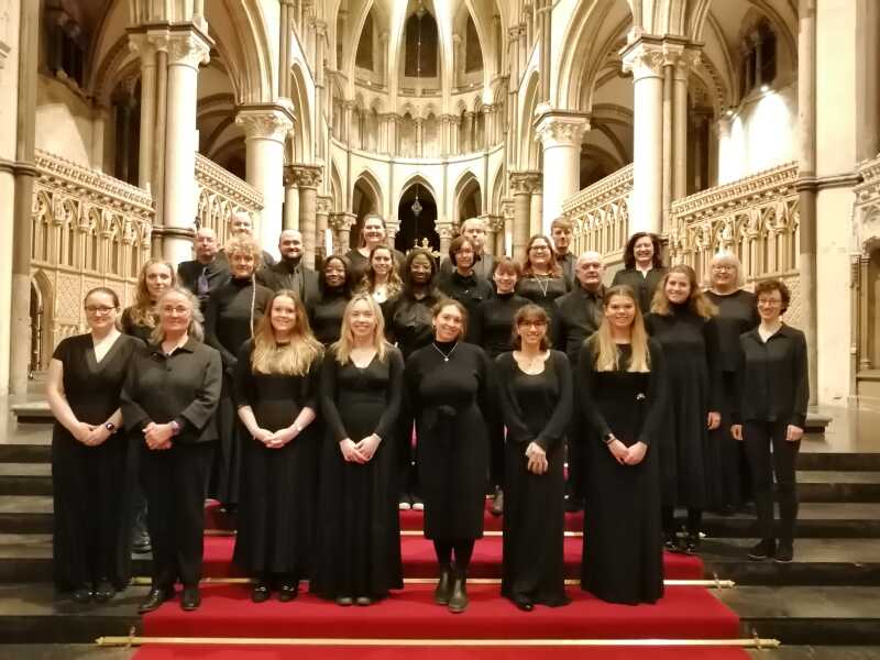 Mixed group of singers wearing all black standing on steps in Canterbury Cathedral
