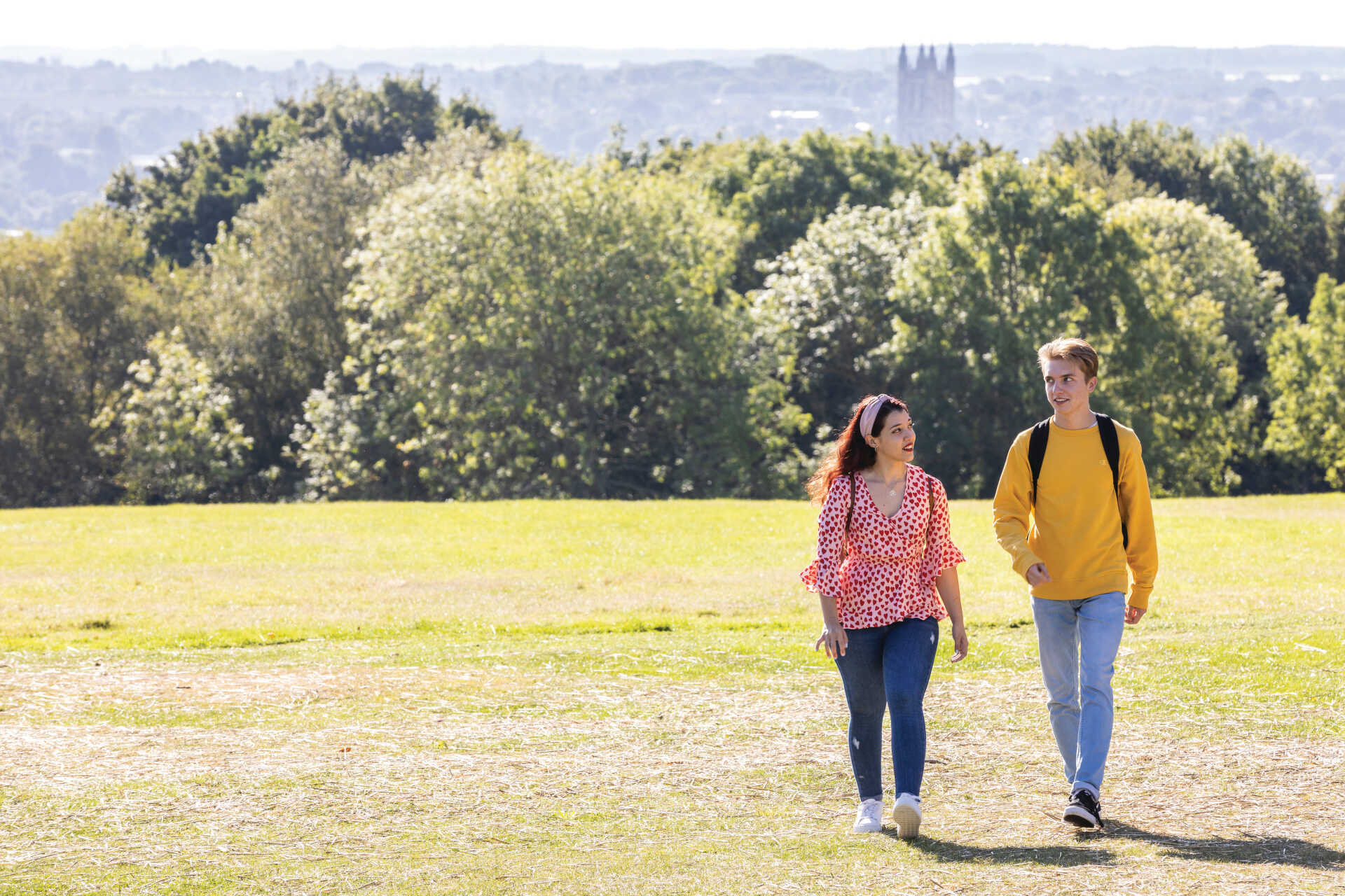 Male and female student walking on Canterbury campus lawns overlooking Cathedral