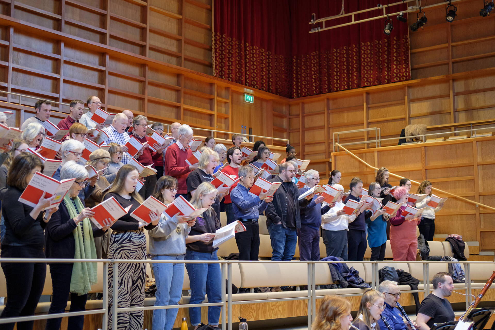 Group of singers on tiered seating in rehearsal in a concert-hall
