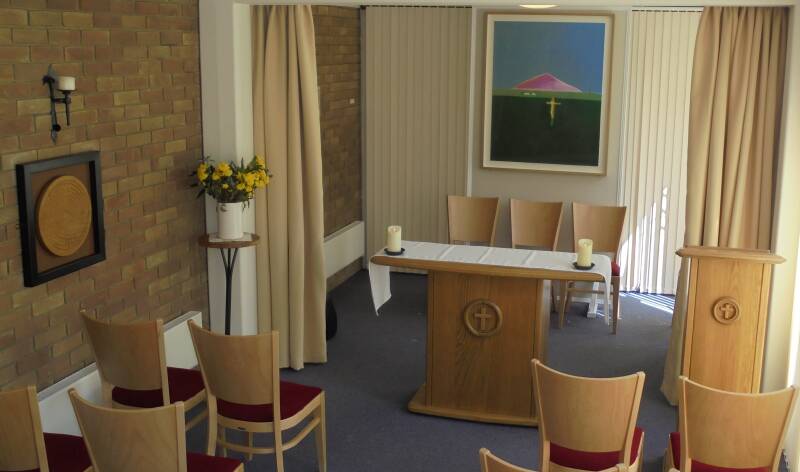 Interior view of a small Christian chapel, with chairs and candles.