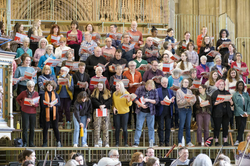 Group of mixed singers rehearsing in raised rows in a cathedral setting