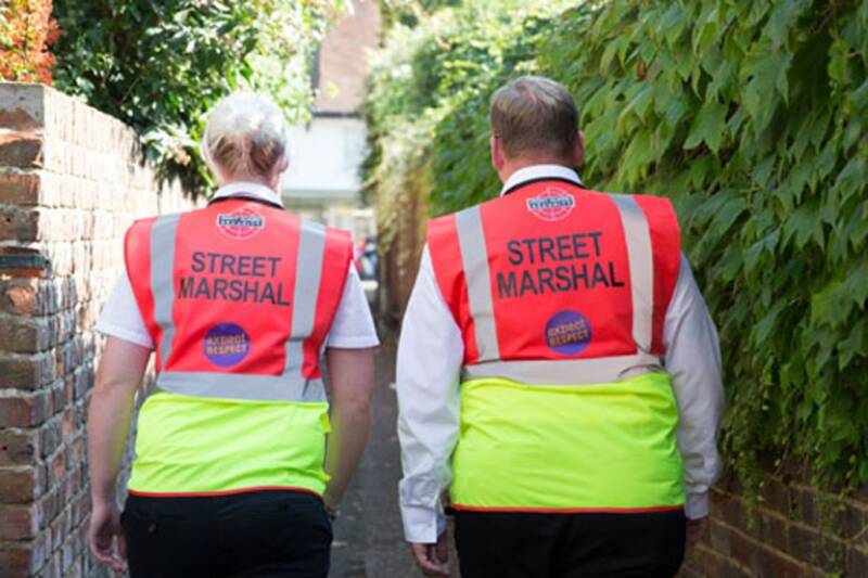 Two people wearing high-visibility jackets with text reading 'Street Marshall' and 'Expect Respect'.