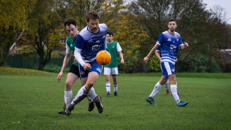 Men playing football on a grass pitch