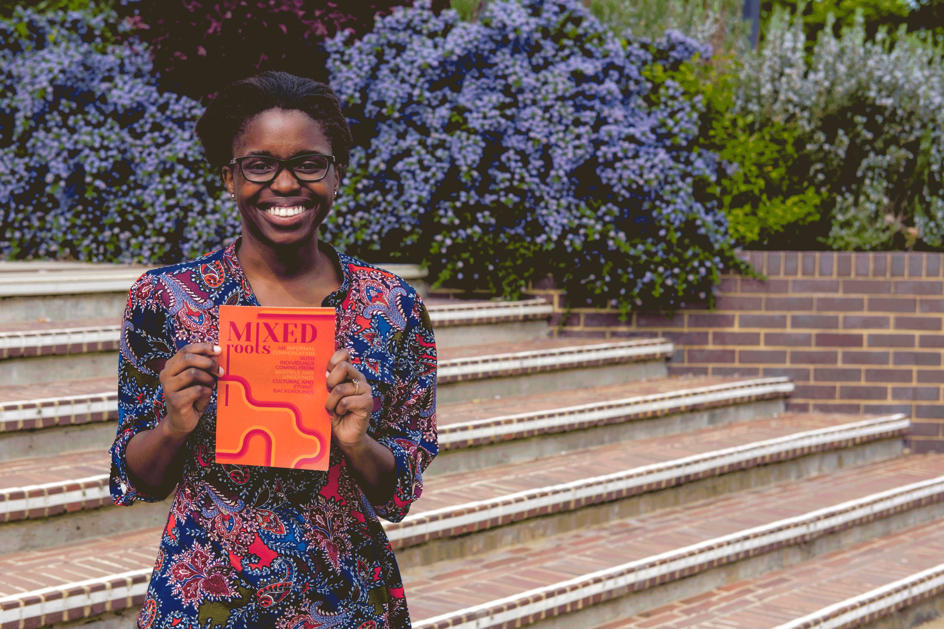 Student Grace smiling holding Mixed Roots event poster