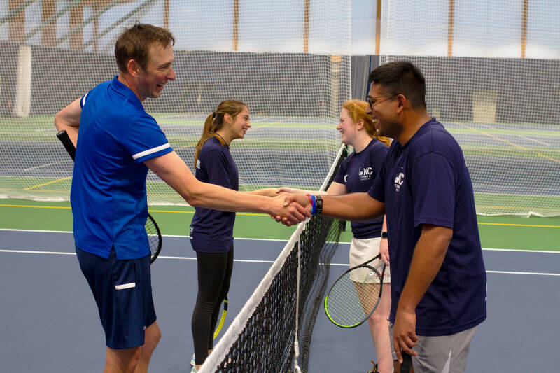 Tennis Club members and our lead coach, Nick Skelton, shake hands after a tennis match.