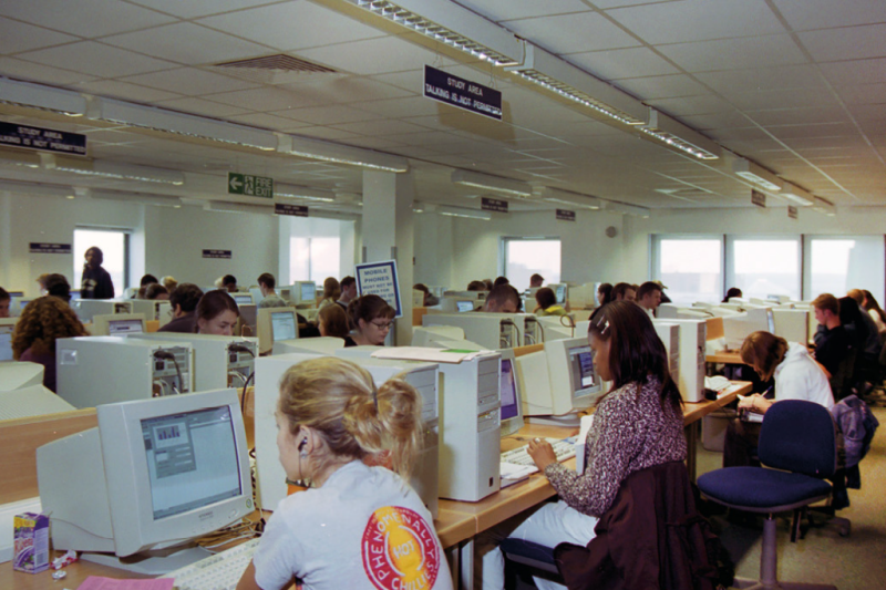 Students at old fashioned desktop computers in a university Library.