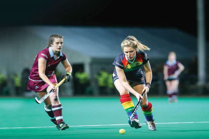 Two female hockey players compete to reach the ball first
