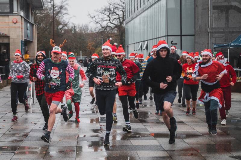 people running in festive outfits across plaza on Canterbury campus