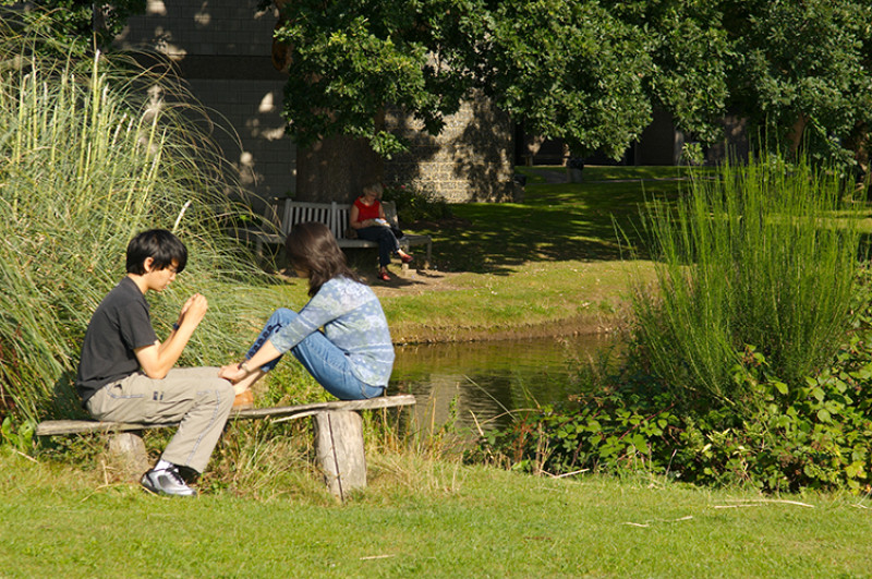 Students relax by Keynes College duck pond