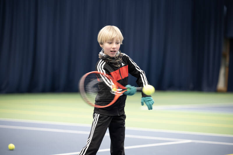 Young boy returning a shot during a coaching session.