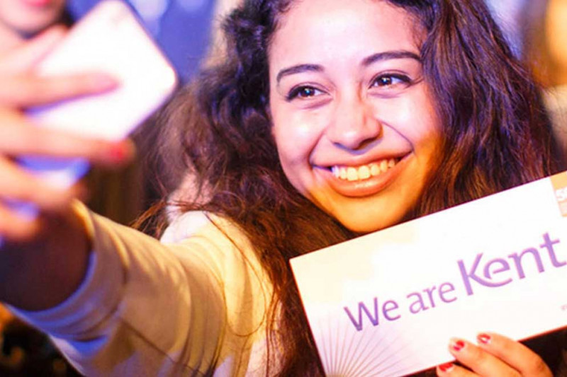 Smiling student holding 'We are Kent' sign