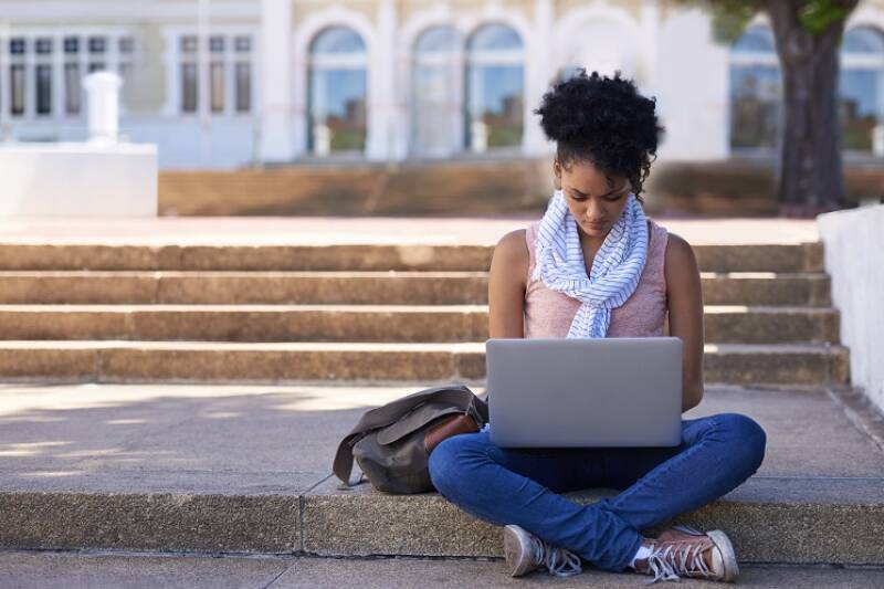 Female Student sits stairs with on laptop