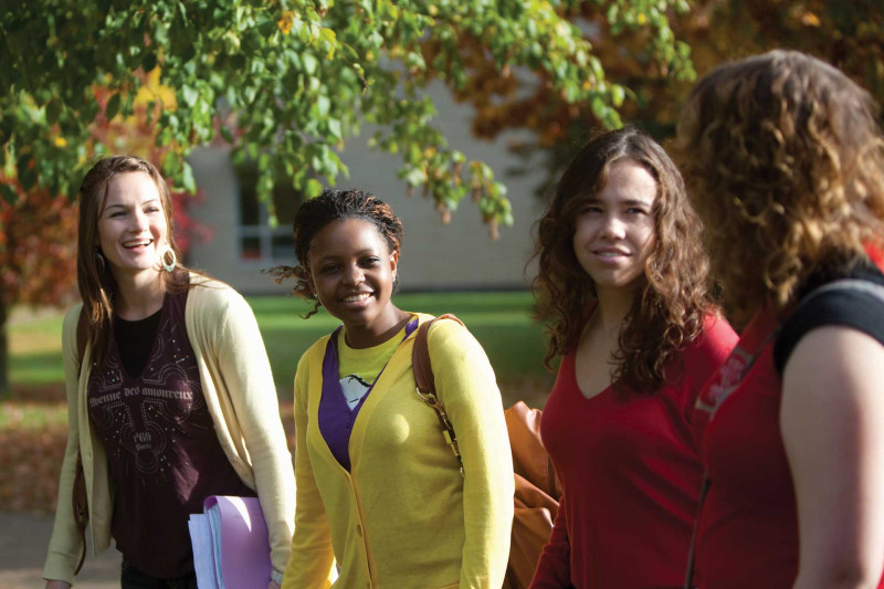 Four female students talking and walking across campus