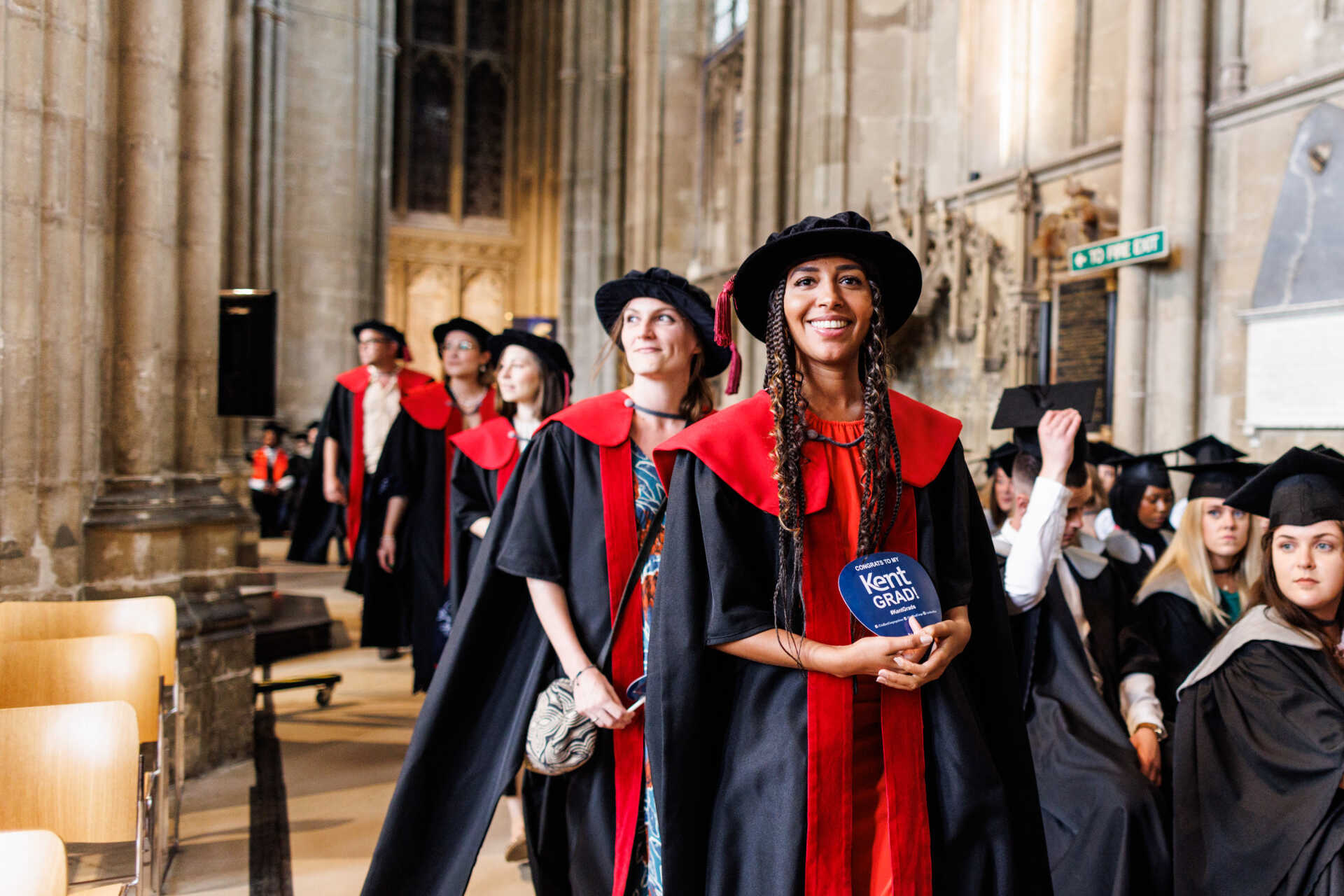 Postgraduate students in Canterbury Cathedral walk to graduate.