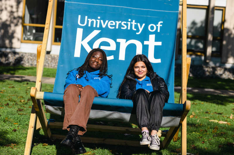 students sit on a deck chair looking at the camera