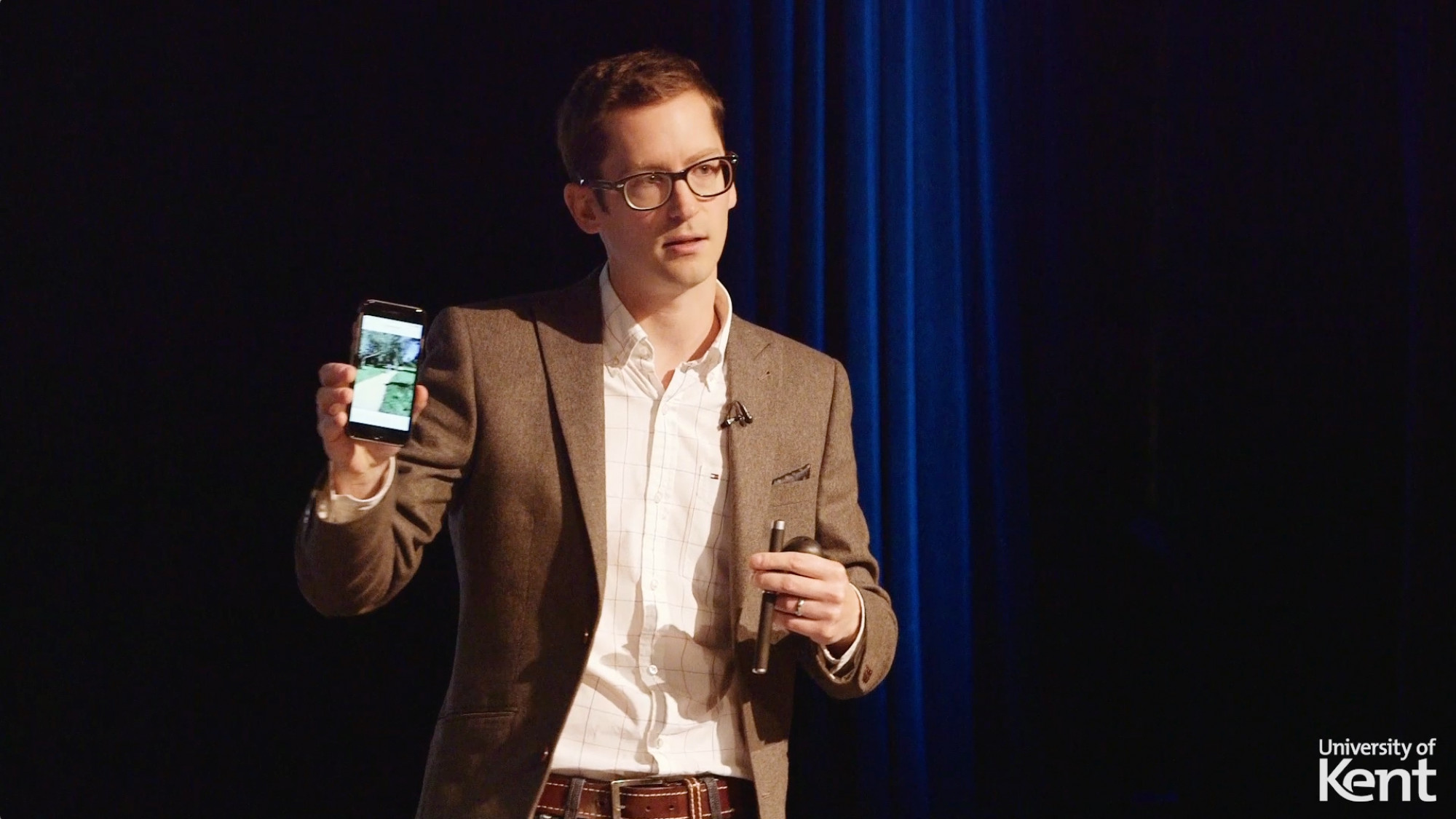 Academic holding up a smartphone to audience in a lecture
