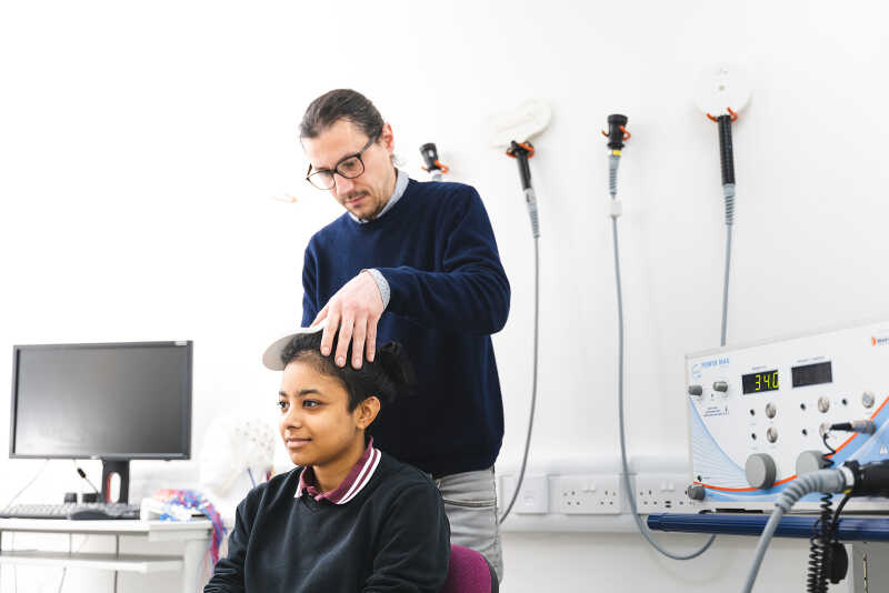 A researcher and a student conduct a TMS experiment