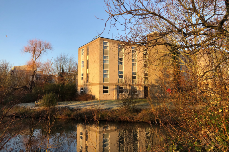 Looking across a still pond to Keynes College on a sunny winters day.