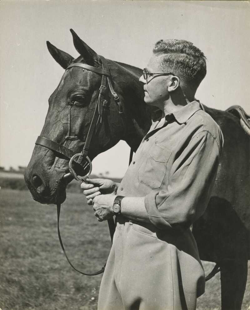 A black and white photograph of Giles with a dark haired horse.