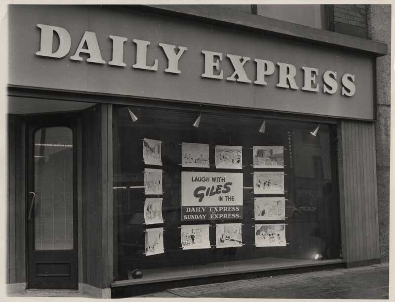 A black and white photograph of the Daily Express offices with a Giles display in the windows