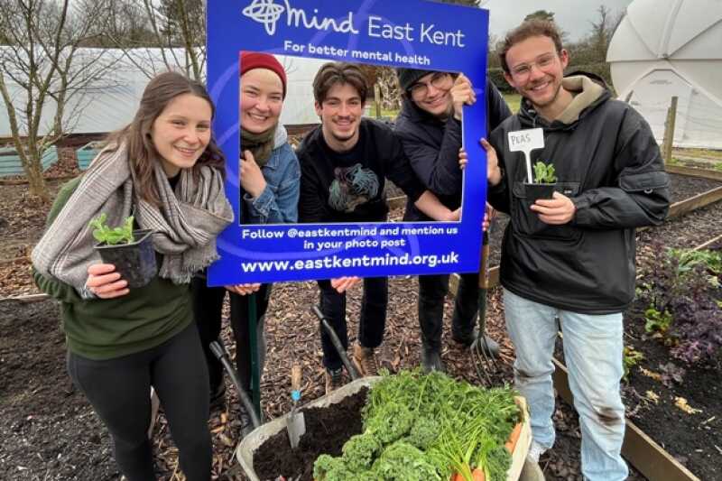 Students posing with an East Kent Mind Sign at a garden.