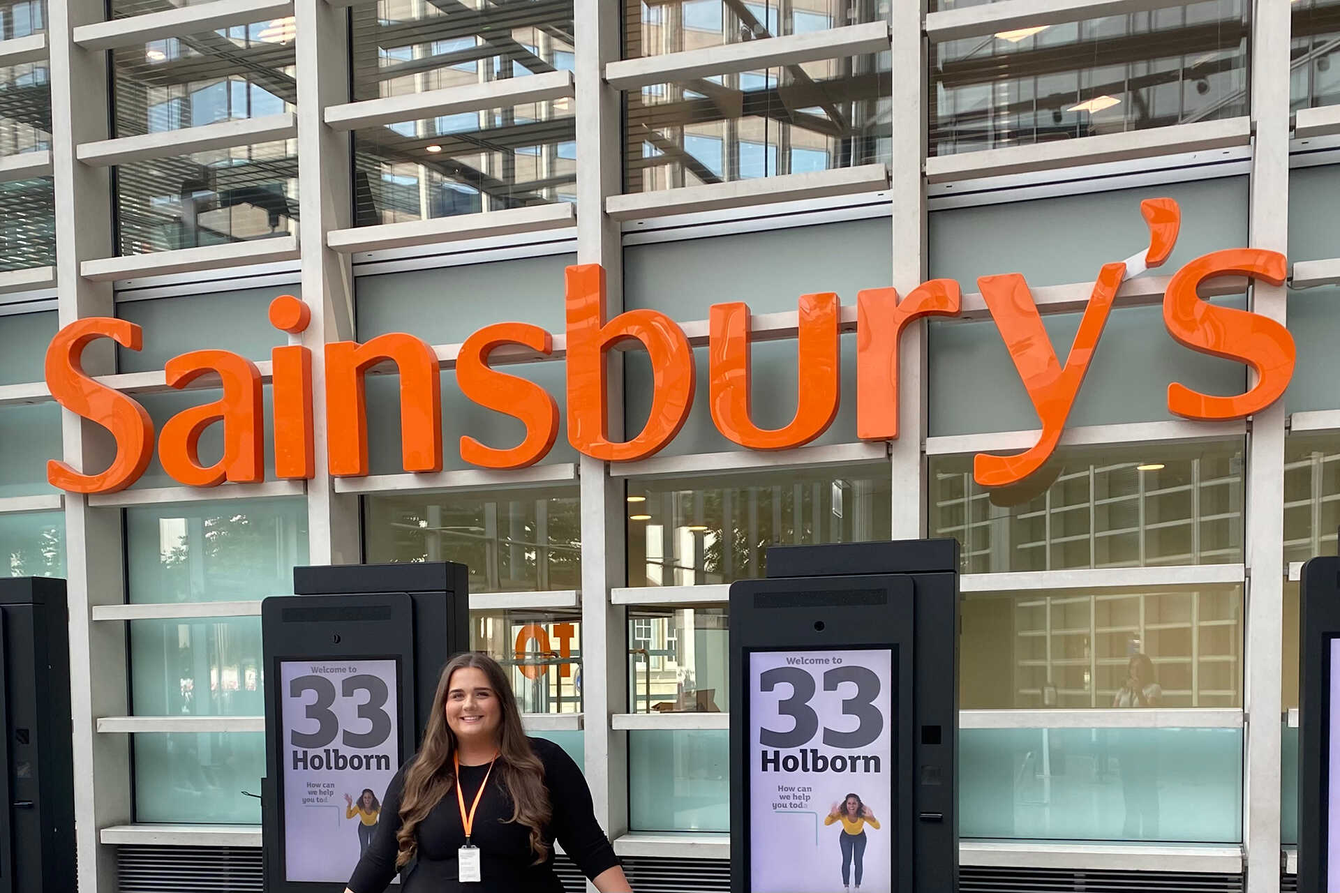 Girl in front of Sainsbury's sign