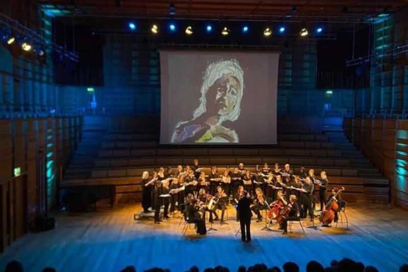 Choir and strings performing beneath a projected image